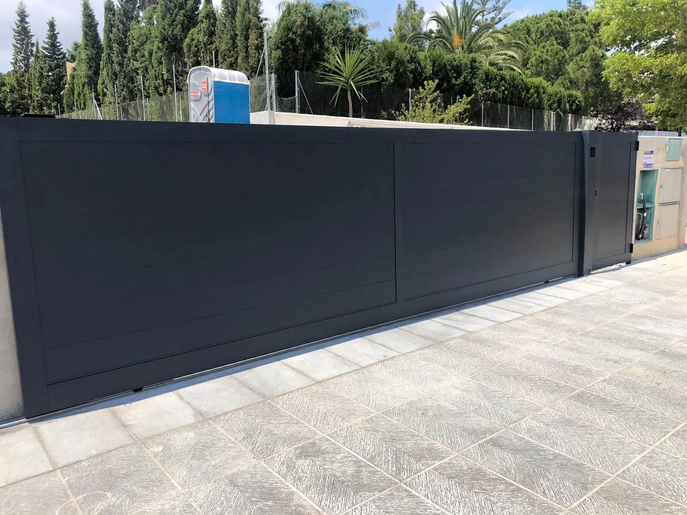 Puerta corredera automática de aluminio gris antracita con puerta peatonal en un chalet de Málaga